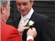 Wedding Toastmaster assists guest with button hole at Vaulty Manor, Essex